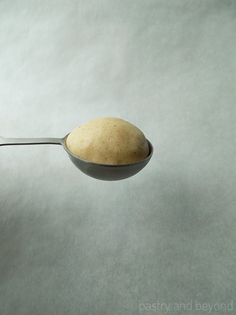 Cinnamon cookie dough ball in a teaspoon.