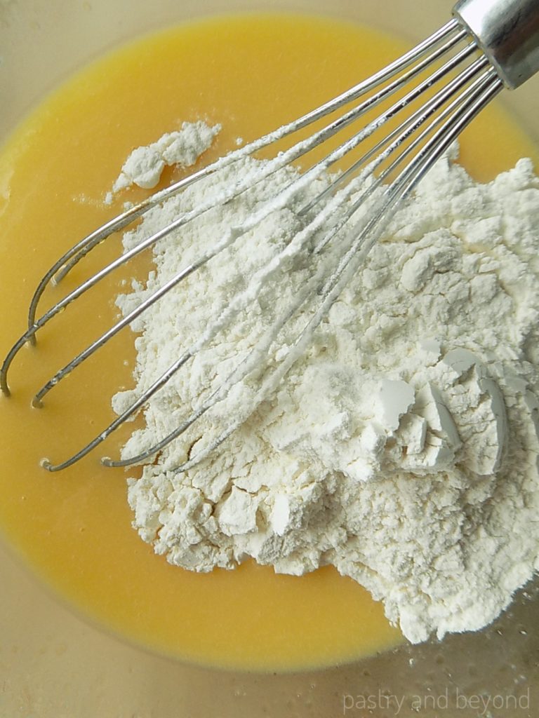 Flour mixture in a bowl with a whisk, added to the wet ingredients.