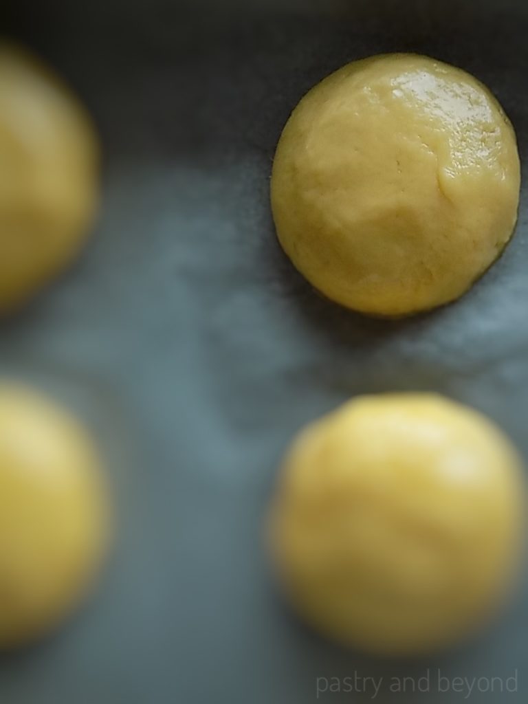 Vanilla cookie dough rolled into balls and placed on parchment paper.