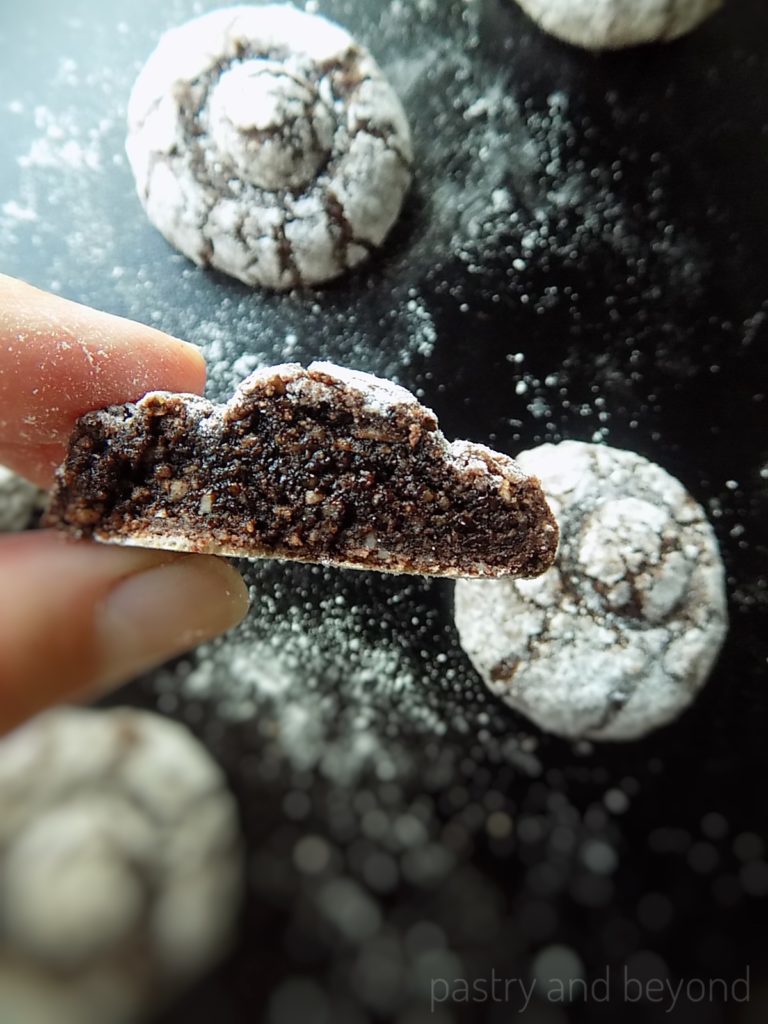 Hand holding half of the gluten free chocolate crinkle cookie.