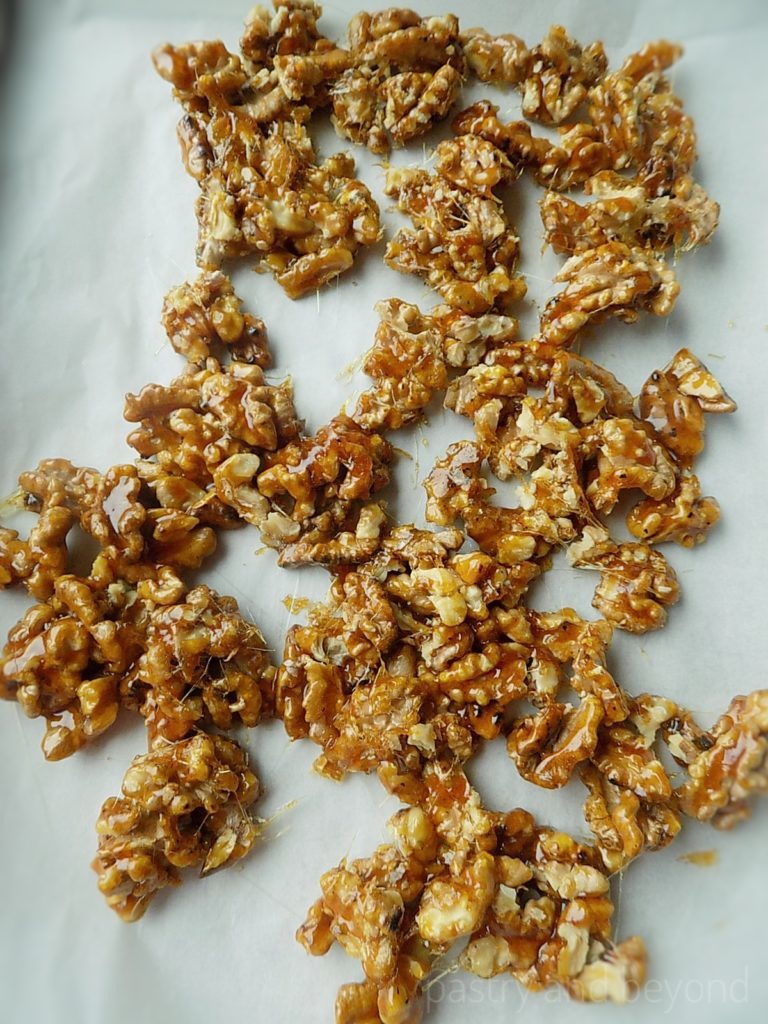 Caramelized walnuts on a parchment paper.