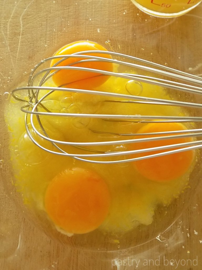 Eggs and sugar mixture in a bowl with a whisk.