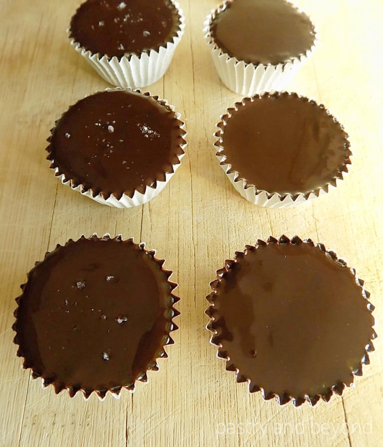 Chocolate caramel cups with sea salt in a row, plain chocolate caramel cups in another row. 
