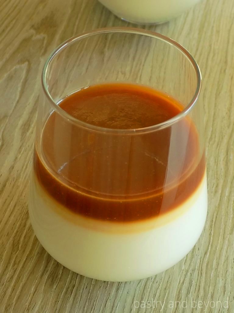 Caramel milk pudding in a serving glass on a wooden surface.