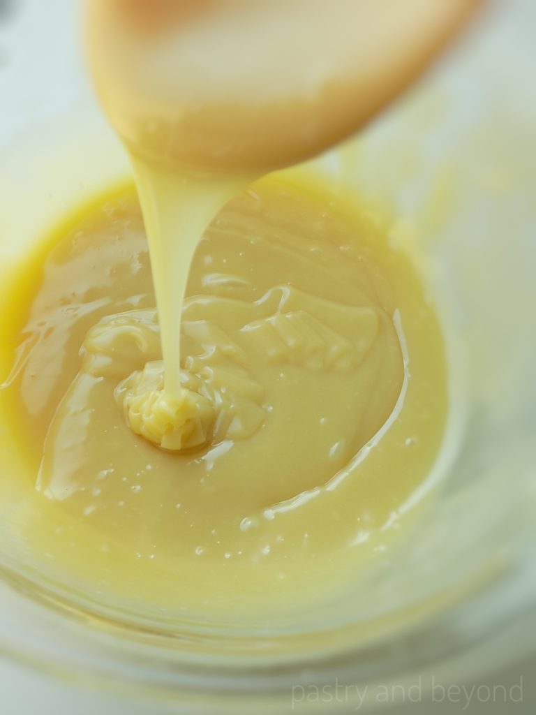 White chocolate ganache is pouring from a spoon.