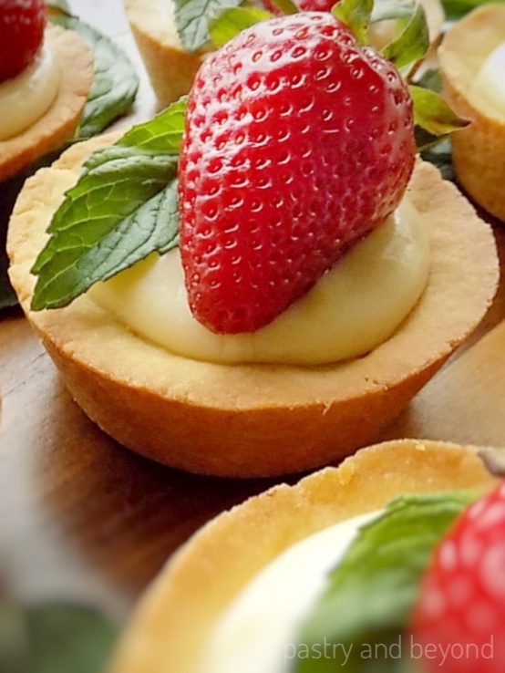 Cookie cups filled with pastry cream, topped with strawberry and mint.