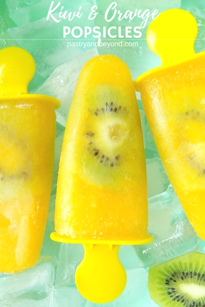 Orange popsicles with kiwi slices in a bowl that is full of ice cubes.