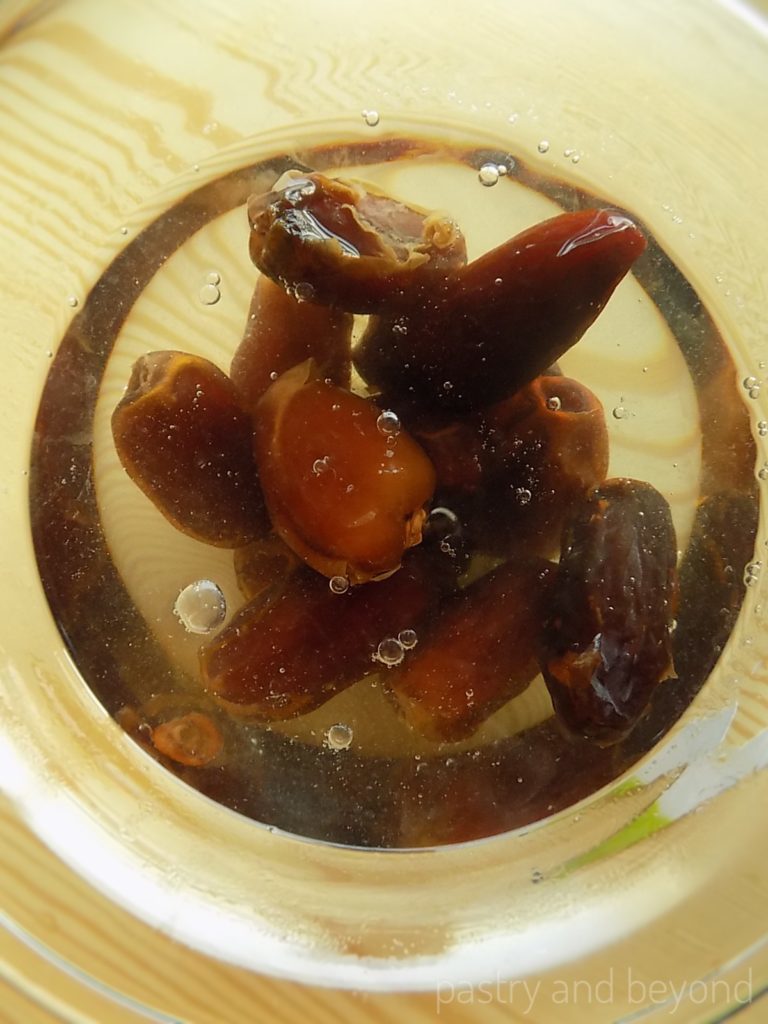 Dates soaked in water in a glass bowl.