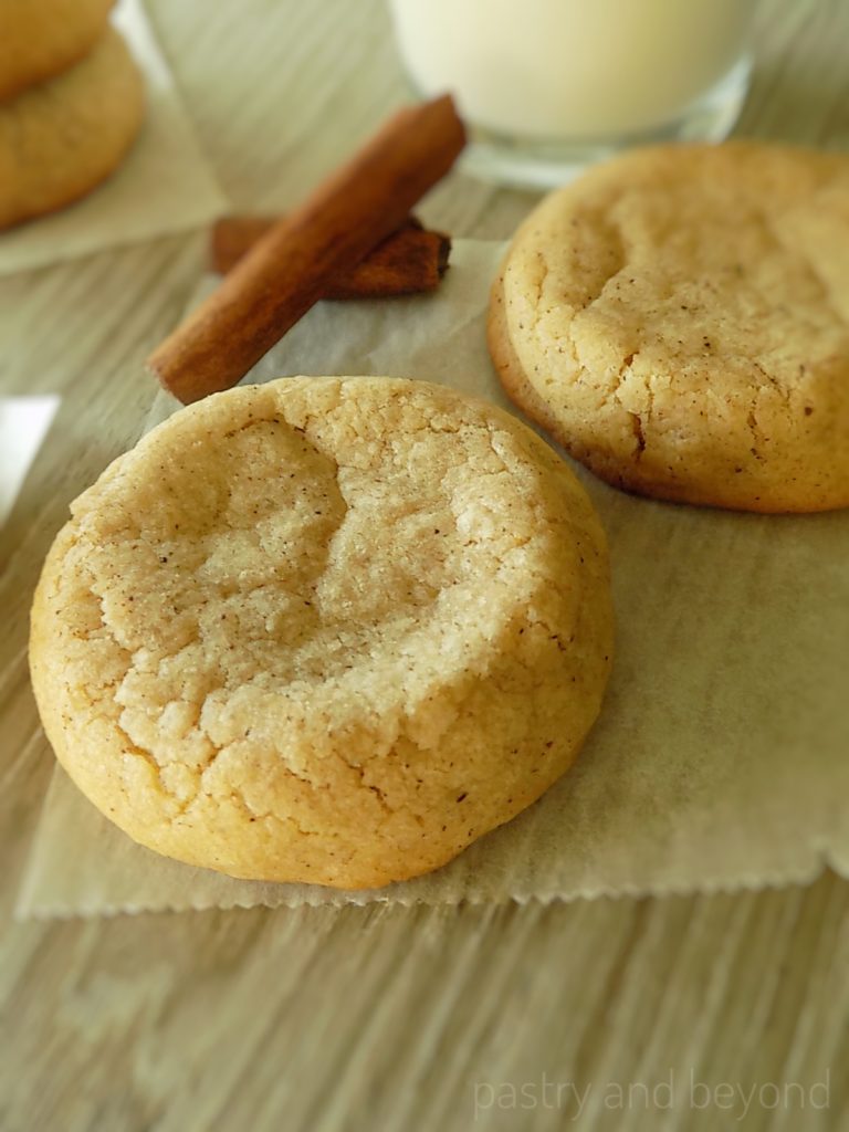 Soft cinnamon cookies with cinnamon sticks on a parchment paper.