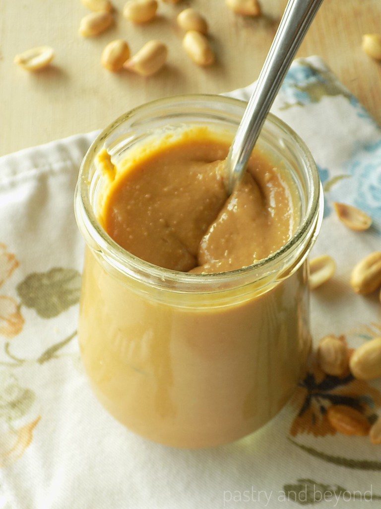 Healthy Peanut Butter in a jar with a spoon on a flower table mat. 