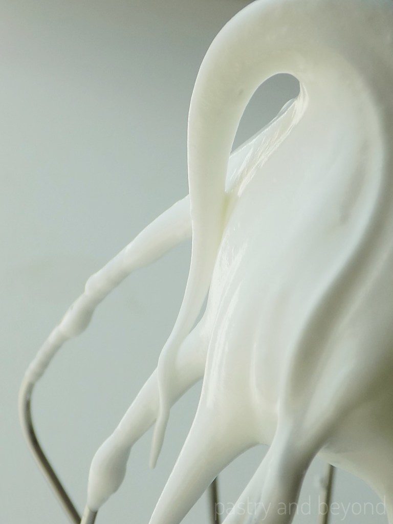 Meringue forms a hook when whisk is lifted. 