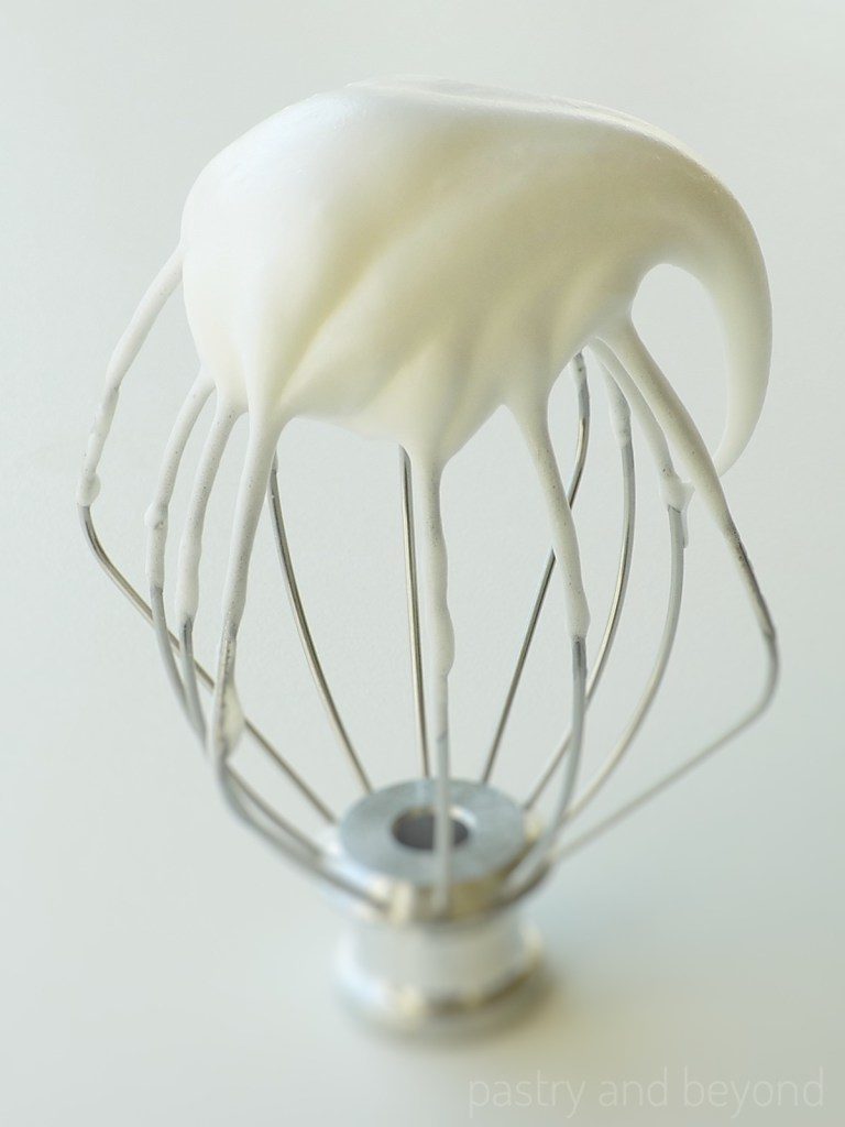 Meringue falls over itself on a whisk after mixing the egg whites at medium-high speed.