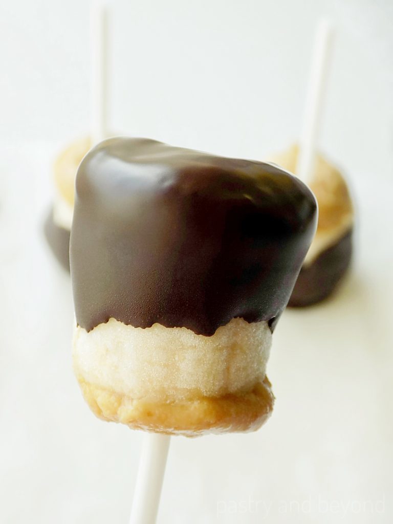 Chocolate covered frozen banana bites with peanut butter on a stick.