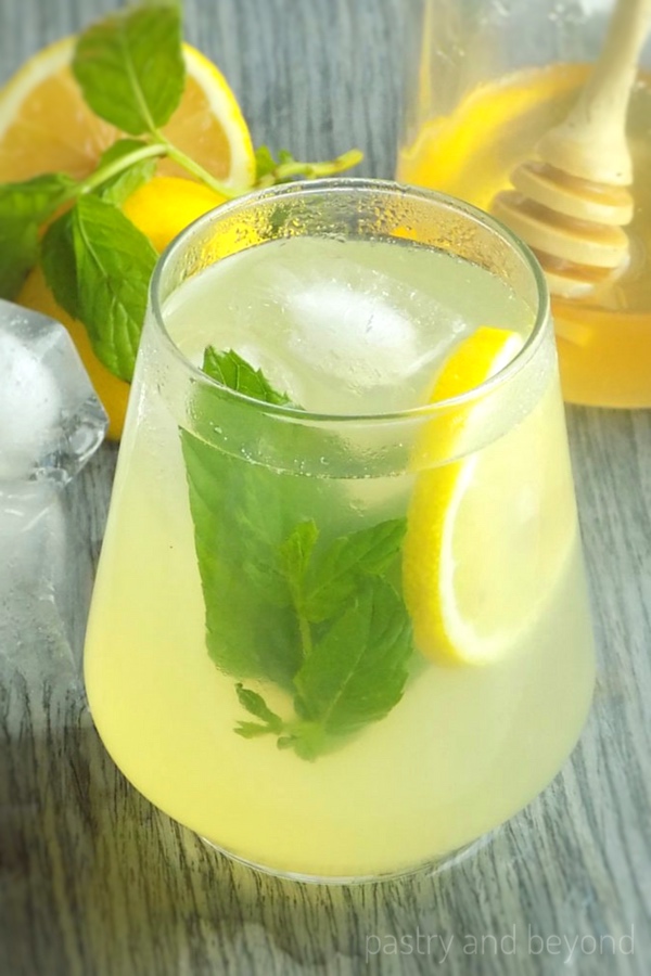 Honey lemonade in a glass with lemon slice and mint leaves.