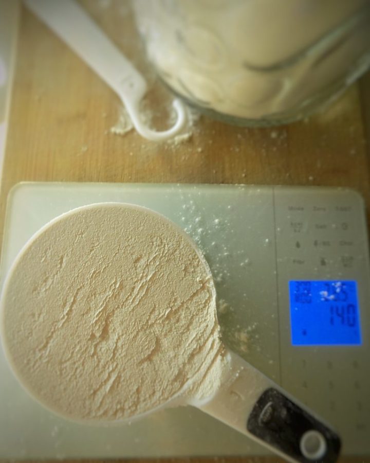 Flour in a measuring cup on a digital food scale.