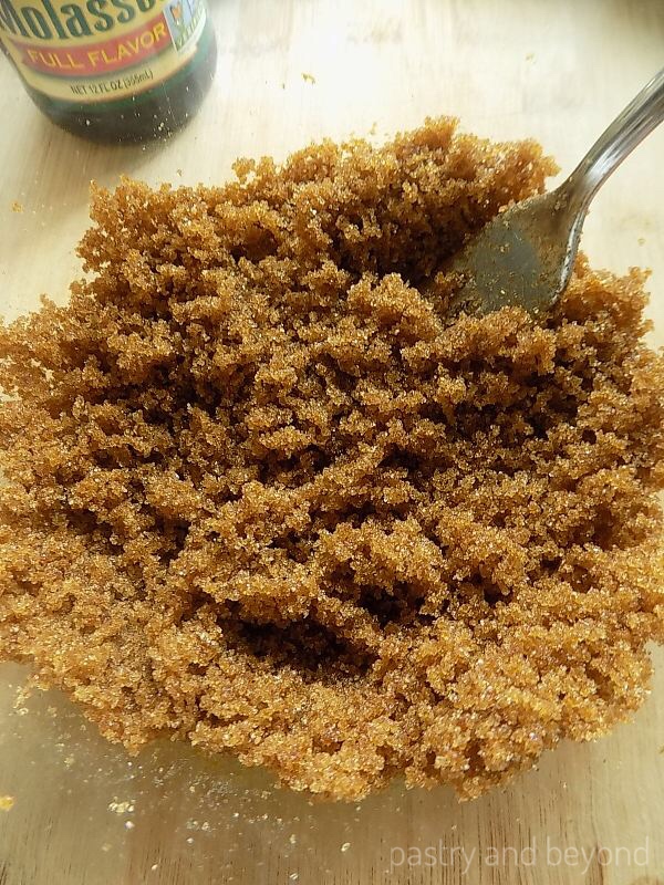 Dark brown sugar in a bowl with a fork after sugar and molasses are mixed.