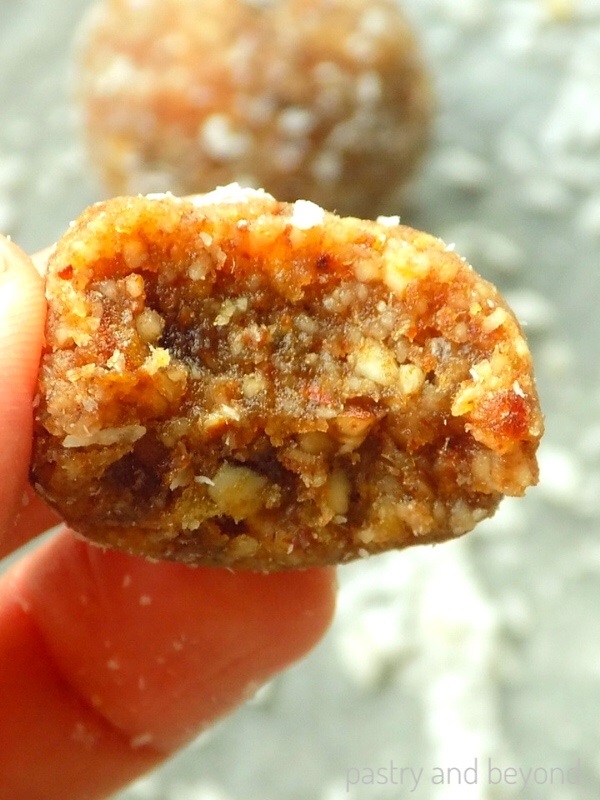 A hand is holding the chewy almond ball that is cut in half.