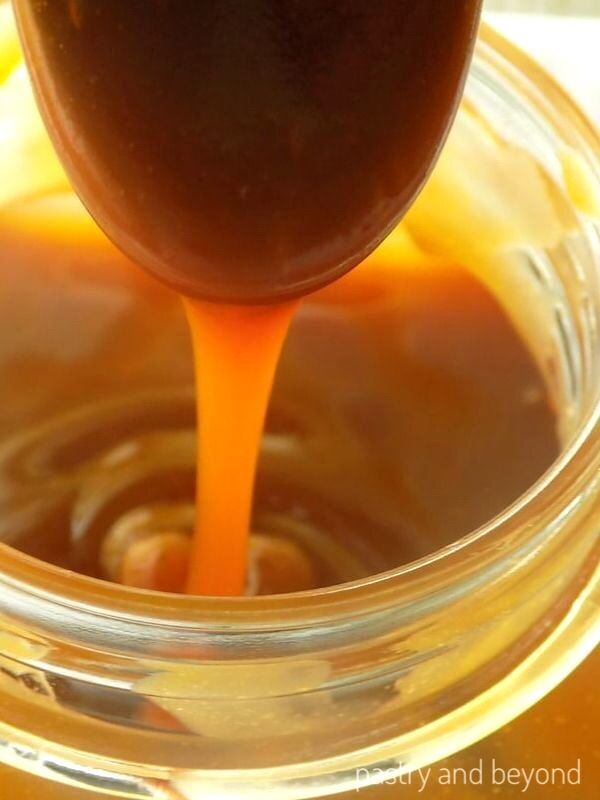 Thick consistency of homemade caramel sauce that is dripping from a spoon after cooled.