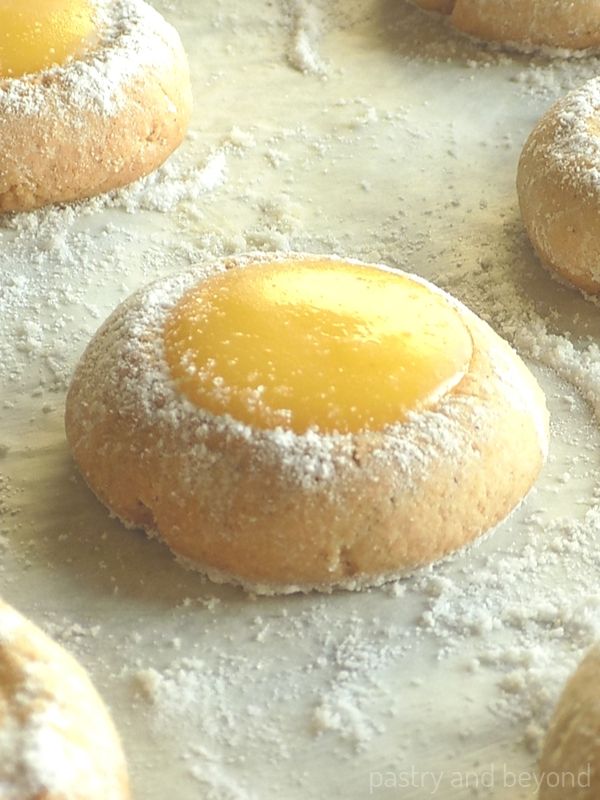 Lemon curd thumbprint cookies with powdered sugar on the edges.