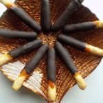 Caramel and chocolate cookie sticks on a brown glass plate.