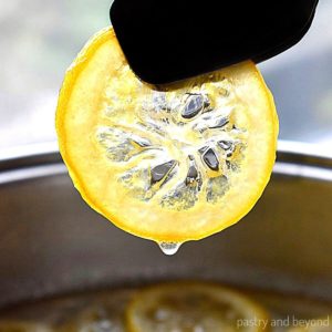 Holding candied lemon slice with tongs.