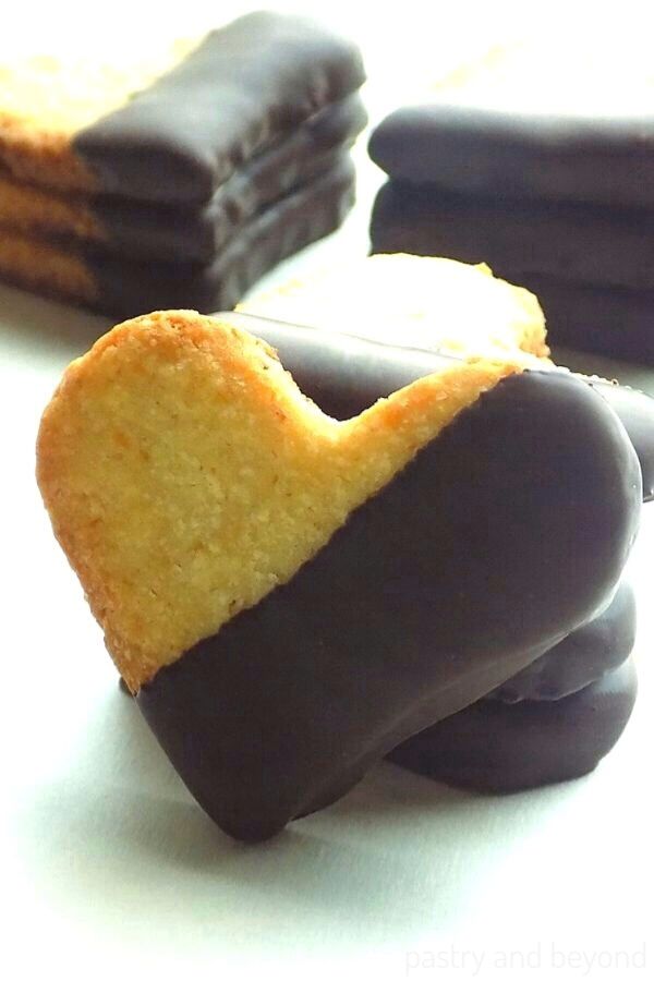 Stacked Heart Shaped Cookies that are dipped on chocolate on a white surface. 
