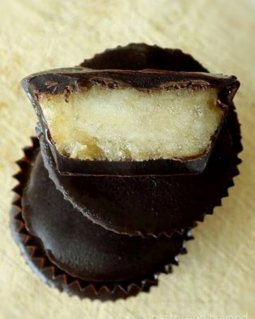 Stacked frozen mashed banana bites in chocolate cups. The top one is cut in half.