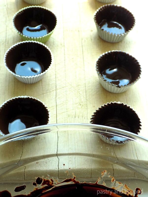 Chocolate covered cupcake liners on a wooden board.