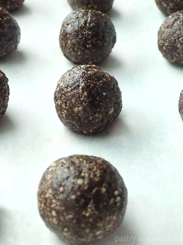 Hazelnut raisin energy balls in a row on baking sheet.