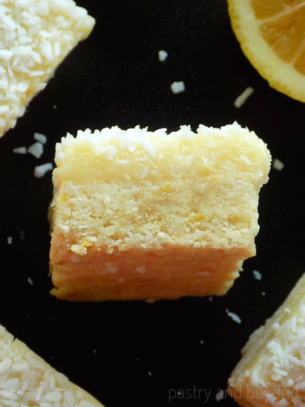Lemon coconut bars with white chocolate on a black surface.