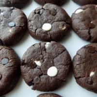 Triple chocolate chip cookies on a white surface.