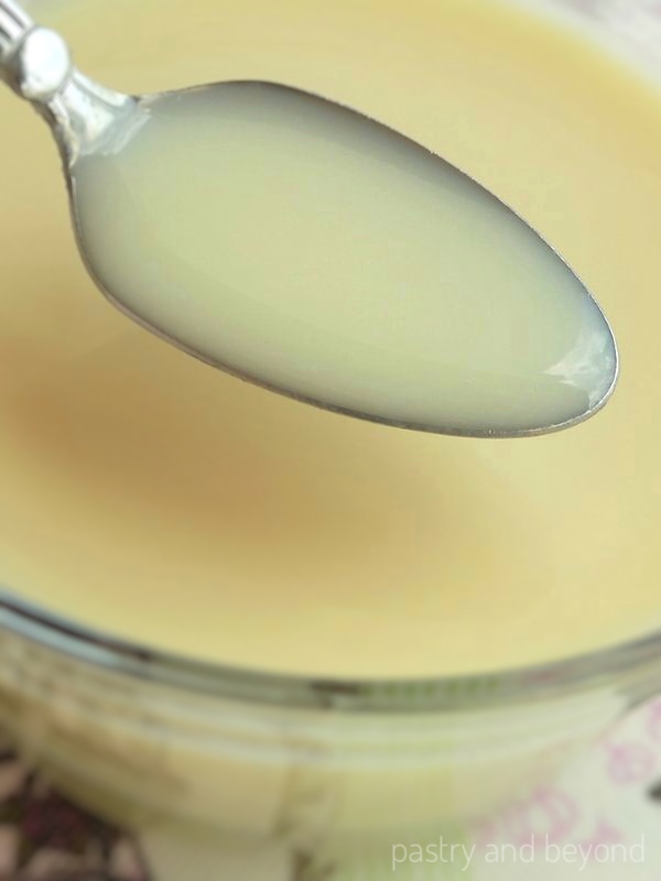 Showing the consistency of the sweetened condensed milk on a spoon.