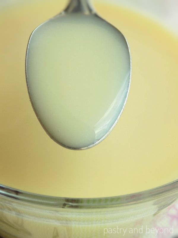 Showing the consistency of homemade condensed milk with a spoon.