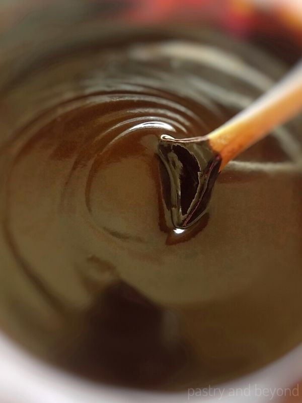 Ganache in a bowl with a wooden spoon.