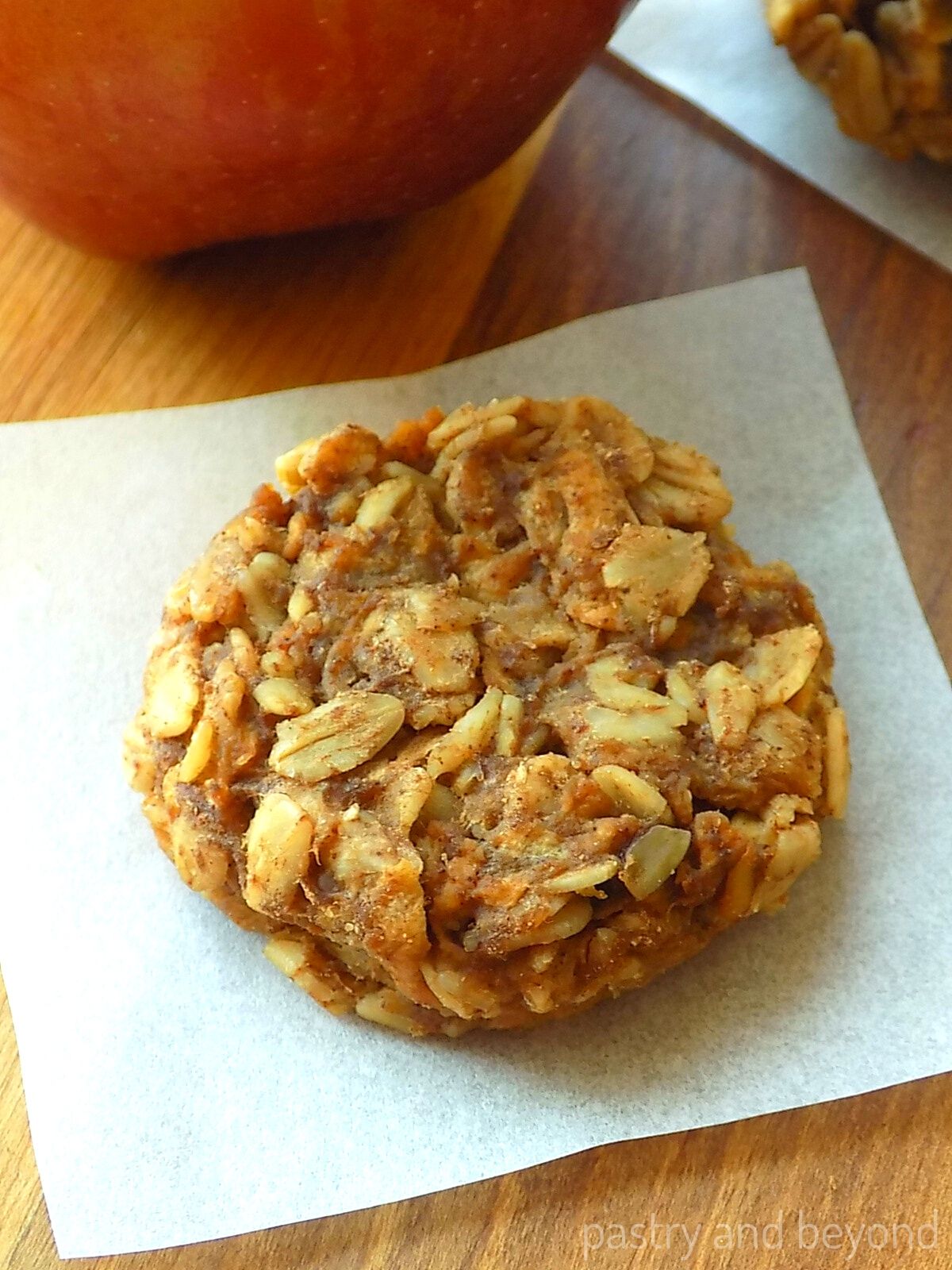 Healthy apple oatmeal cookie with an apple in the background.