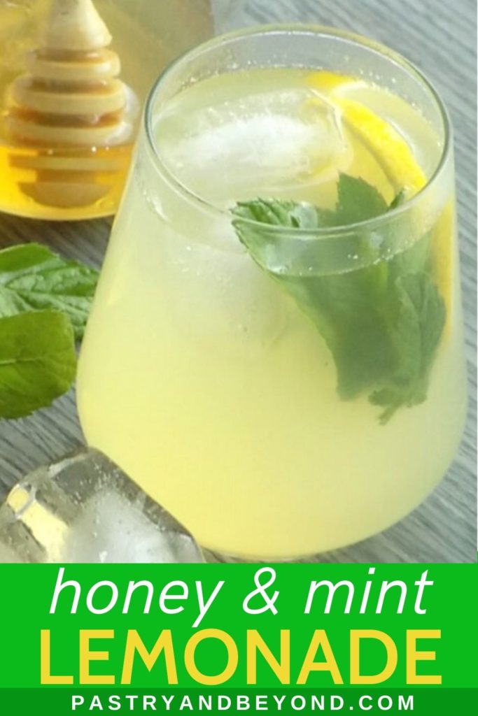 Lemonade in a glass with fresh mint and a slice of lemon, honey in a jar in the background.