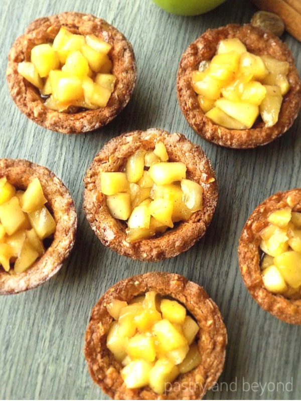 Apple crisp cookie cups on a gray surface.
