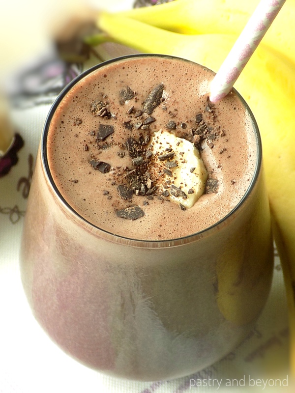 Chocolate peanut butter banana smoothie with shredded chocolate and banana slice on top. 