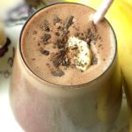 Chocolate peanut butter banana smoothie with shredded chocolate and banana slice on top.