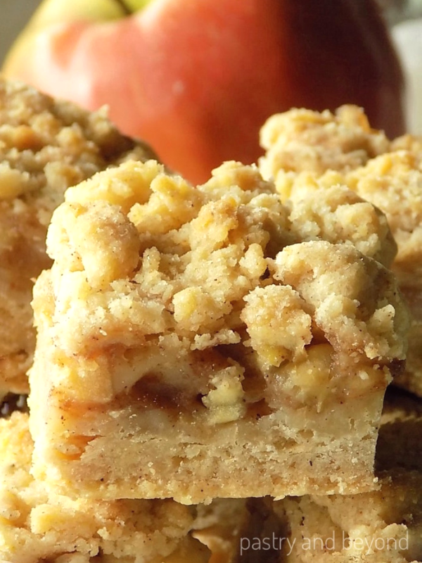 Apple Pie Bars stacked, red apple behind the bars.