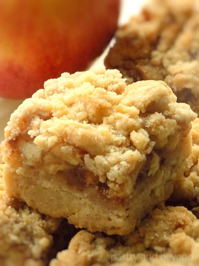 Apple pie bars with crumble topping with apple in the background.