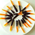 Chocolate dipped candied orange peels on a white plate.