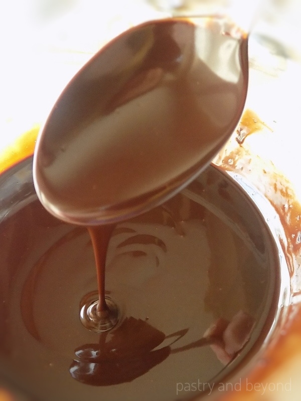 Chocolate ganache is dripping from a spoon.