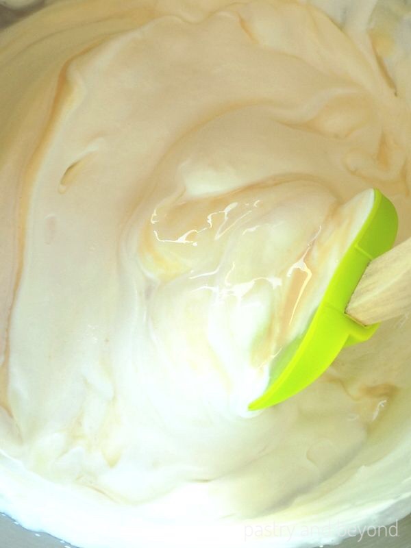 Folding condensed milk into the whipped cream with a spatula.