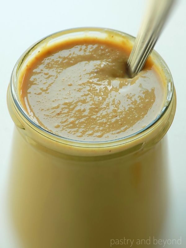 Homemade peanut butter in a jar with a spoon.