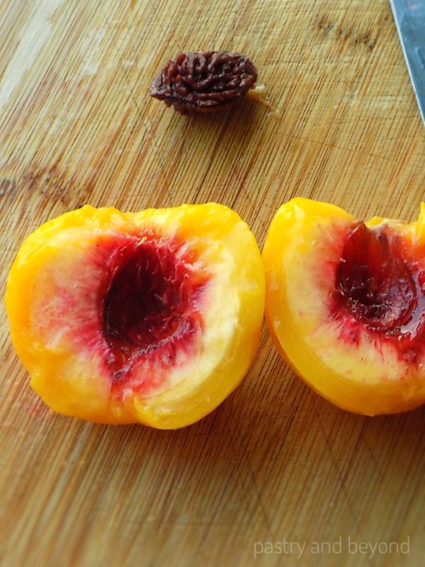 Halved peaches without pit, pit in the background.