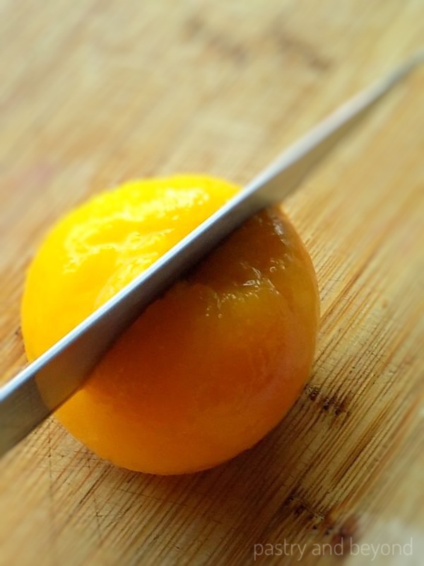 Cutting a peach from middle top to bottom.