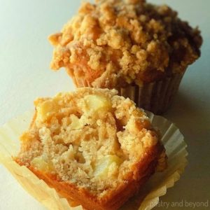Half of the apple crumble muffin that is placed in front of the whole muffin.