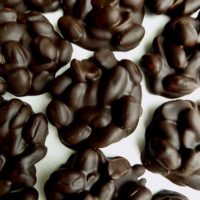Chocolate covered peanut clusters on a white surface.