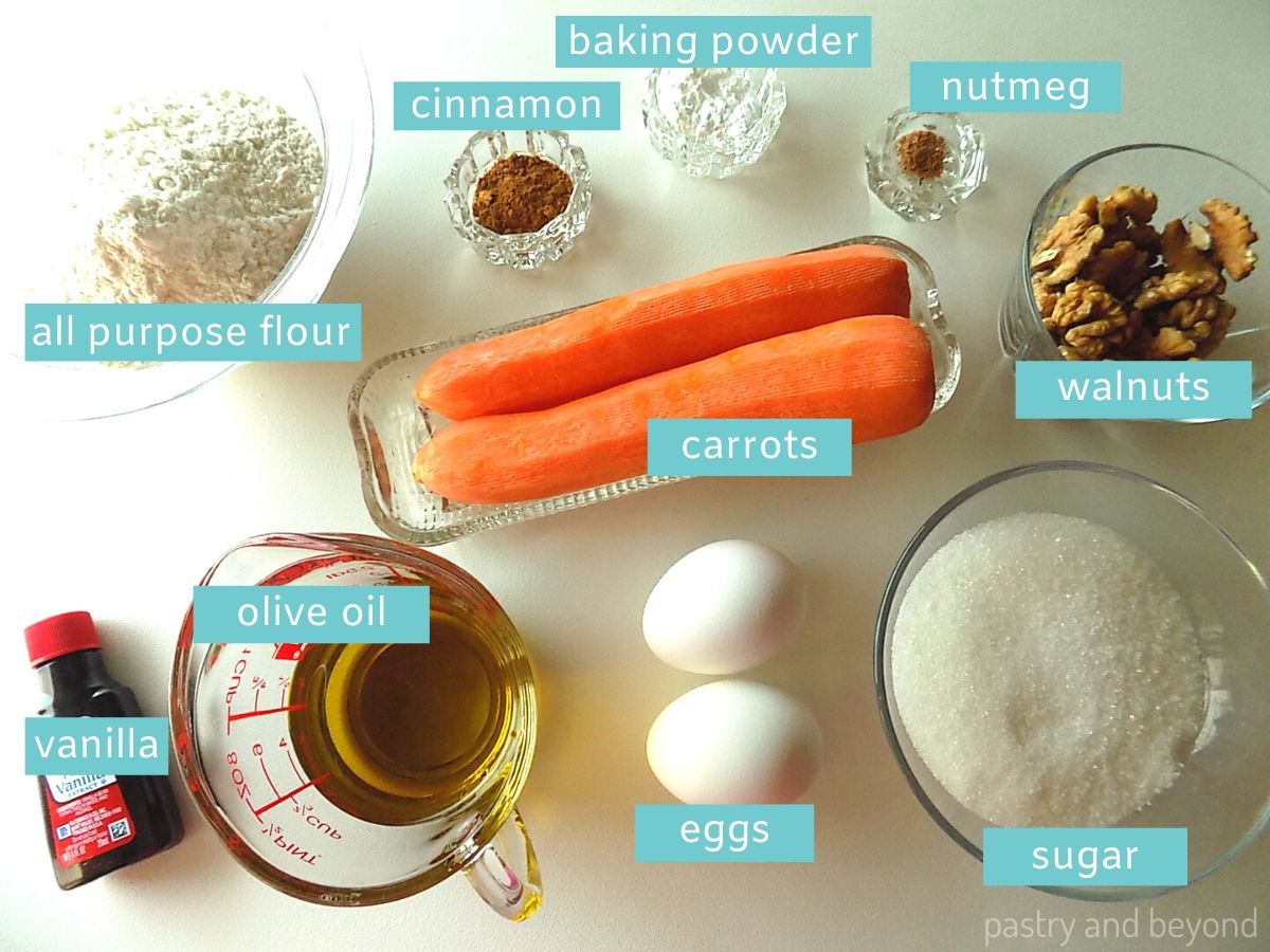 Ingredients for a carrot cake loaf on a white surface.